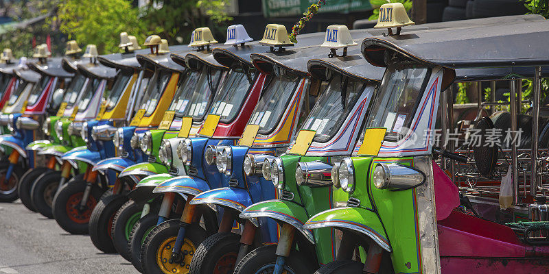 一排排五颜六色的泰国出租车嘟嘟车停在曼谷中心的一条小路上。