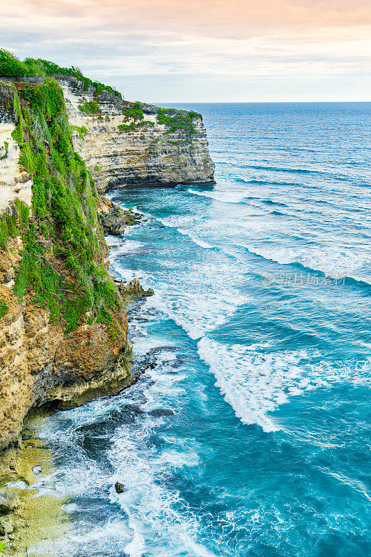 Uluwatu巴厘岛。蓝色的海洋和岩石山，覆盖着热带树木。