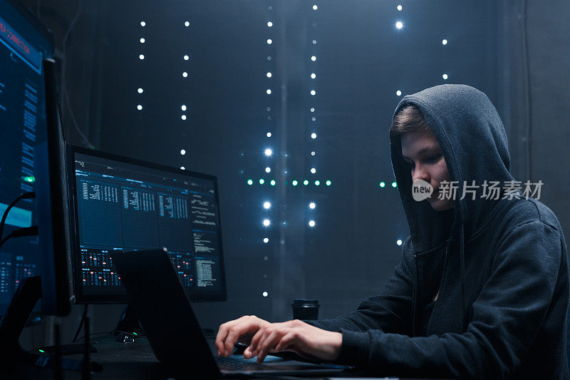 女性黑客在显示器的后台键盘上编码。