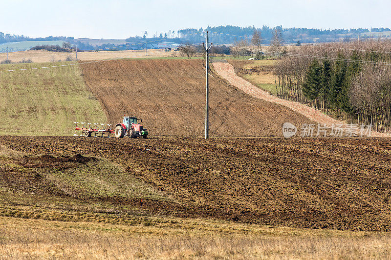 拖拉机犁地。在捷克共和国的农场做春工。农业景观。播种:播种谷物的准备工作
