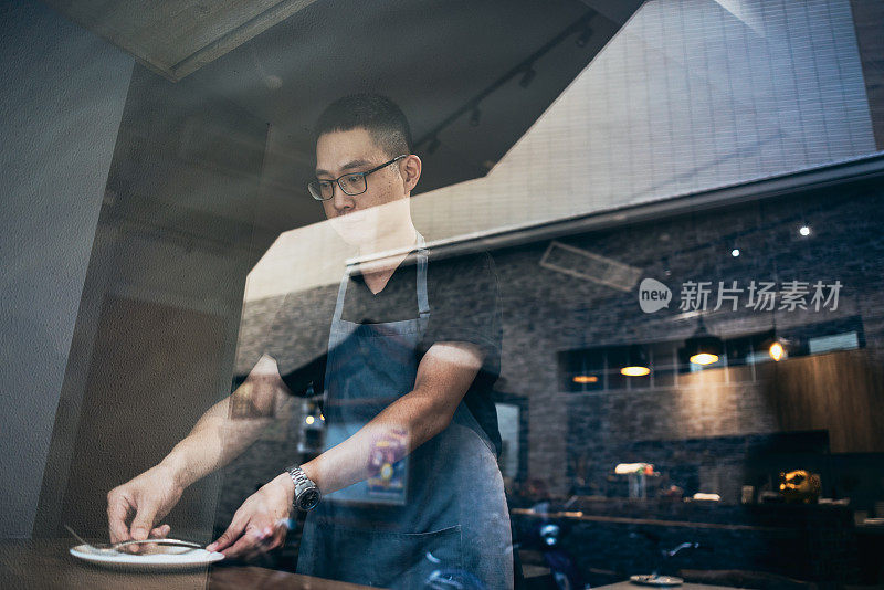 一位亚洲男性餐厅老板在开业前精心准备餐具。