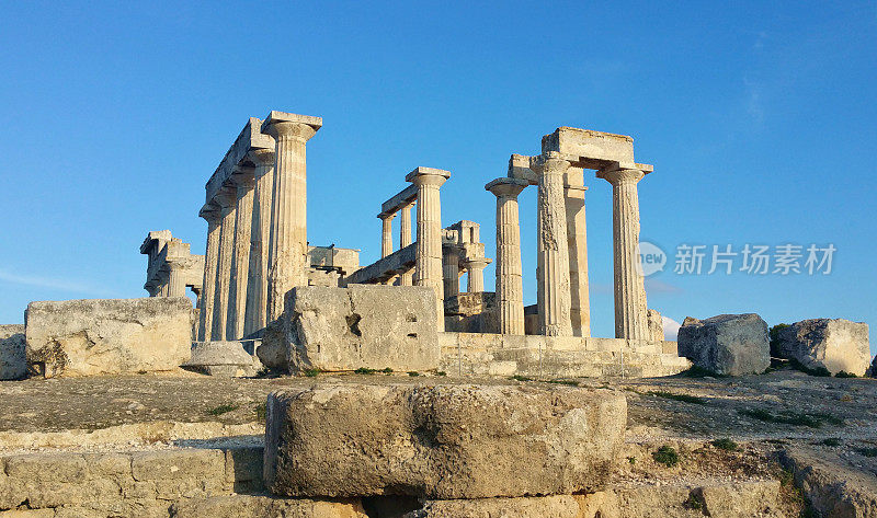 希腊埃吉纳岛上的阿法亚神庙遗址(爱琴海萨罗尼克群岛)上有古罗马石柱，天空蔚蓝金色小时柔光(女神纪念碑)历史遗迹，希腊地中海