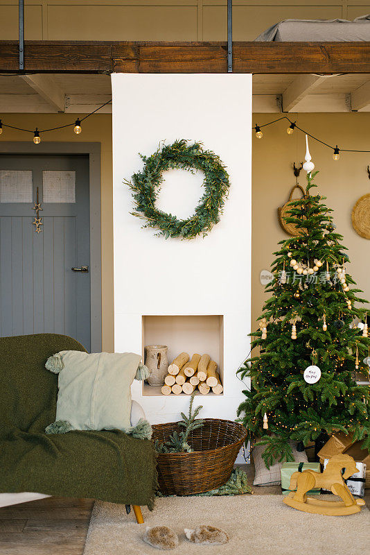 斯堪的纳维亚乡村别墅的时尚圣诞装饰，米色色调。客厅里有壁炉和圣诞树