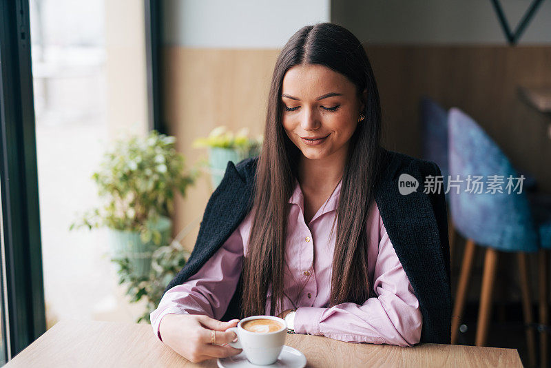 美丽时尚的女孩坐在咖啡馆里喝咖啡