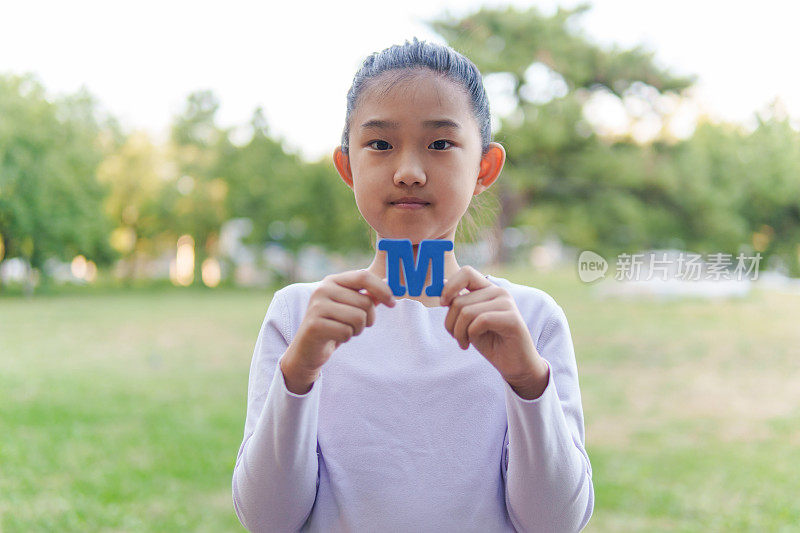 小女孩拿着字母“M”