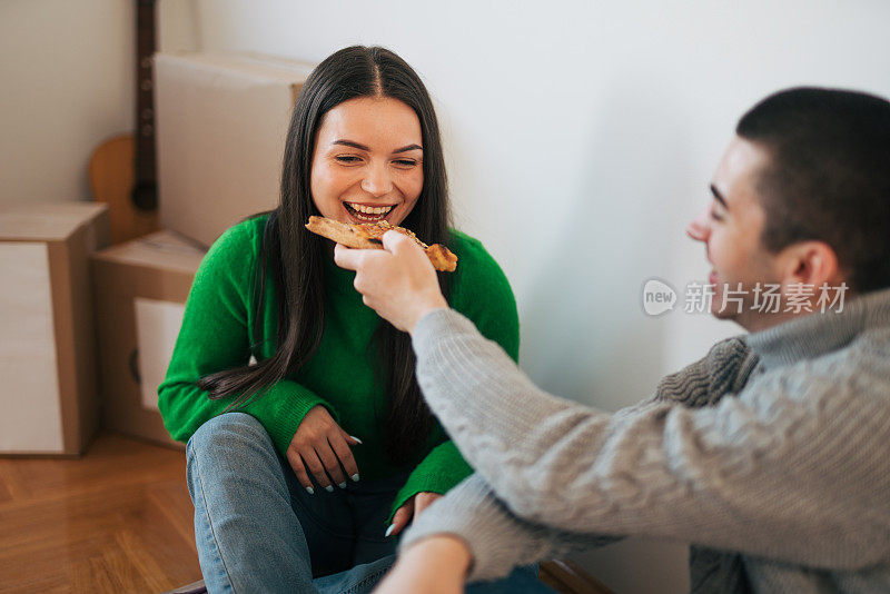 一对年轻夫妇坐在新公寓的地板上。