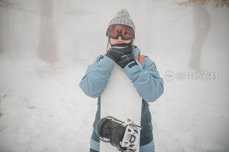 一个戴着滑雪板护目镜的女人站在山上，直视镜头