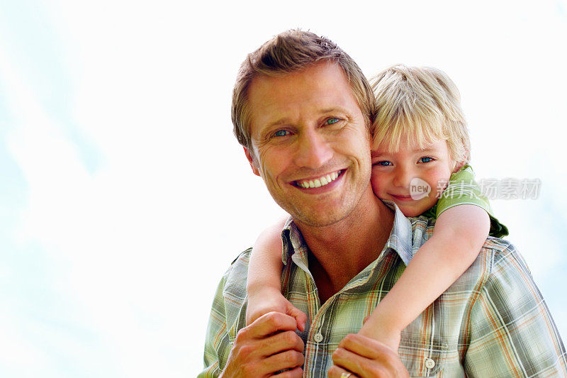 微笑的父亲背着他的儿子背对白色