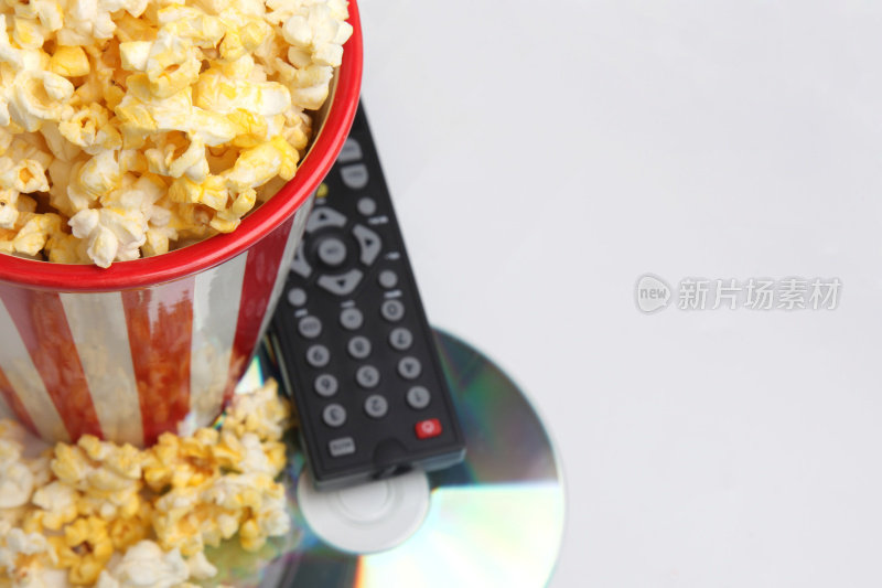 灰色背景上放着DVD、遥控器和爆米花。