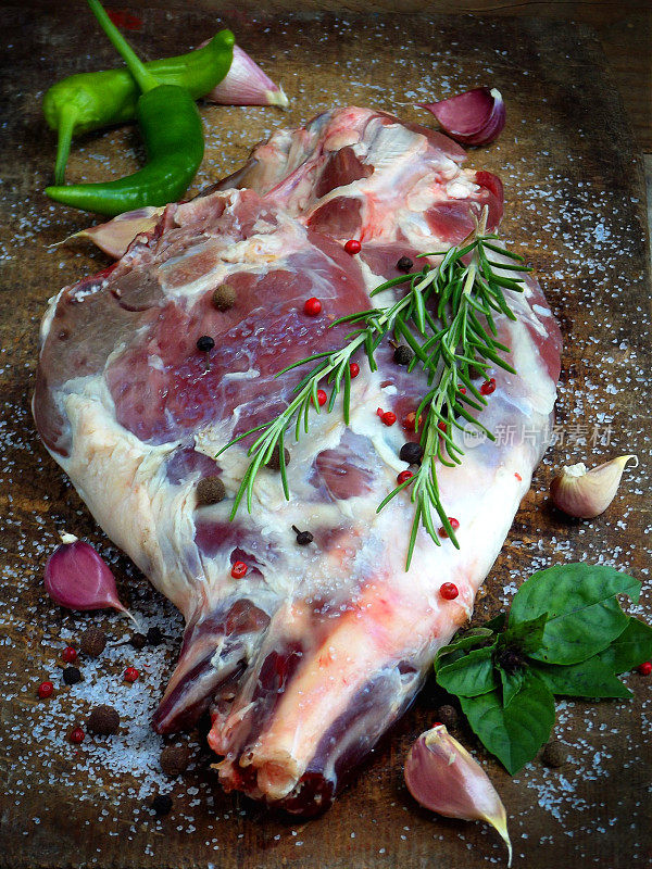 新鲜的生肉。配上香料的羊腿放在木板上，用刀烤，炖，肉饭，烧烤，