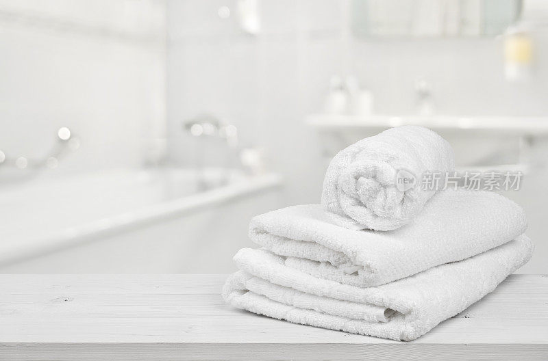 在模糊的浴室背景上折叠的白色浴巾