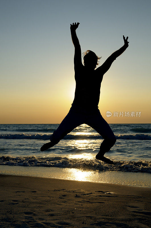 在海边夕阳下跳跃的人