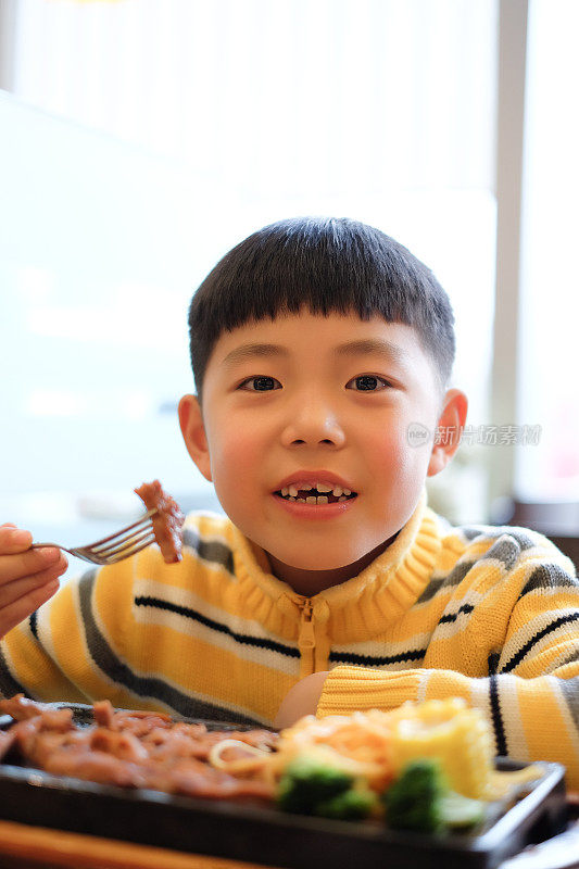 亚洲男孩在餐厅吃牛排