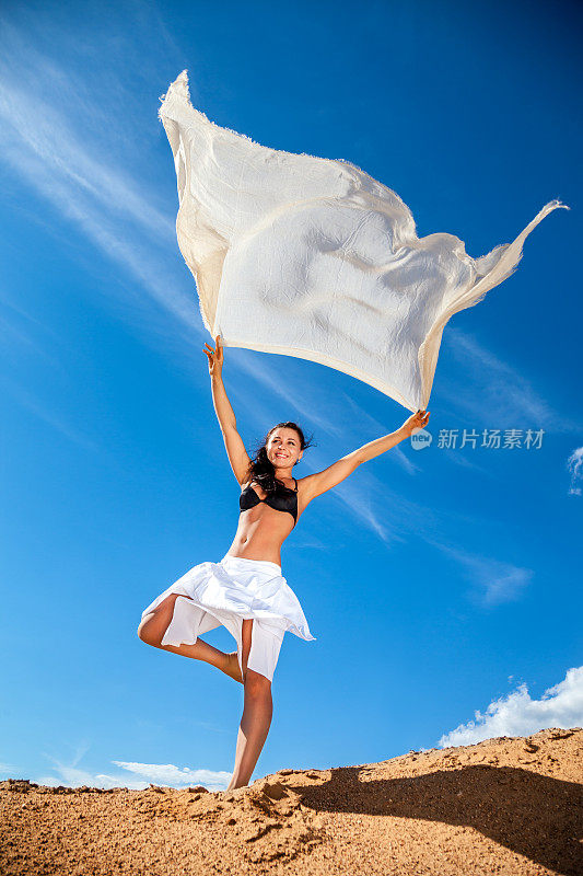 穿着白色裙子在沙滩上跳舞的女孩