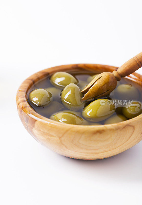 绿橄榄，橄榄油在橄榄木碗。品尝。特写镜头。