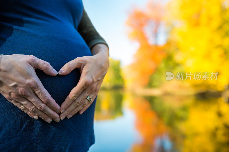 秋天在湖边抱着肚子的孕妇