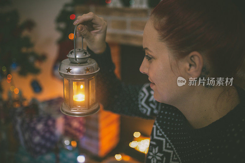 女人的手拿着圣诞灯笼和燃烧的蜡烛