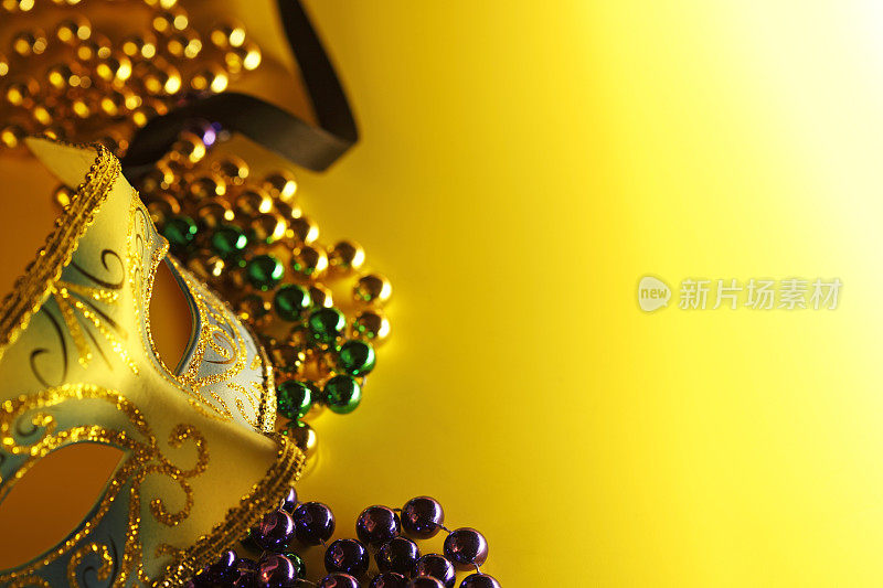 威尼斯面具和黄色背景上的狂欢节珠子