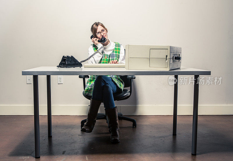 用老式电话和电脑在办公桌前工作的女人