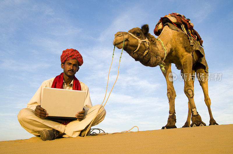 沙漠中骑骆驼的人用笔记本电脑