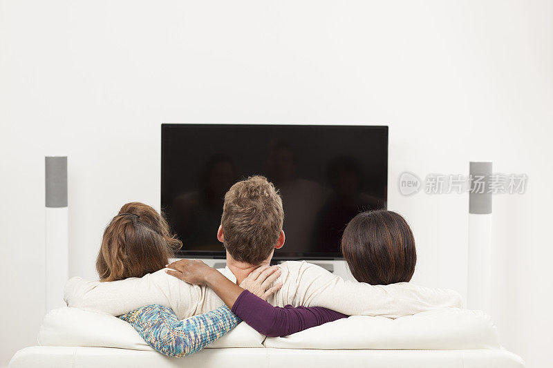 三个人在客厅看电视。