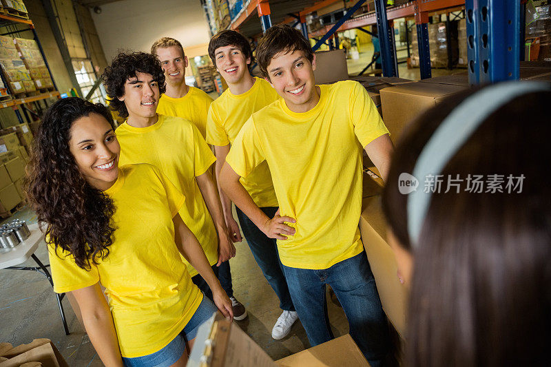 一队青少年志愿者在食品银行的仓库接受指导