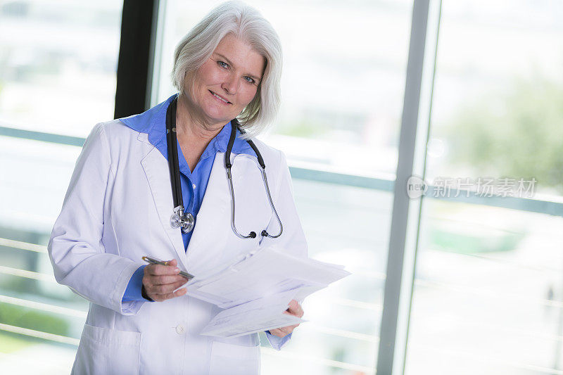 微笑的年长女医生拿着医学文件