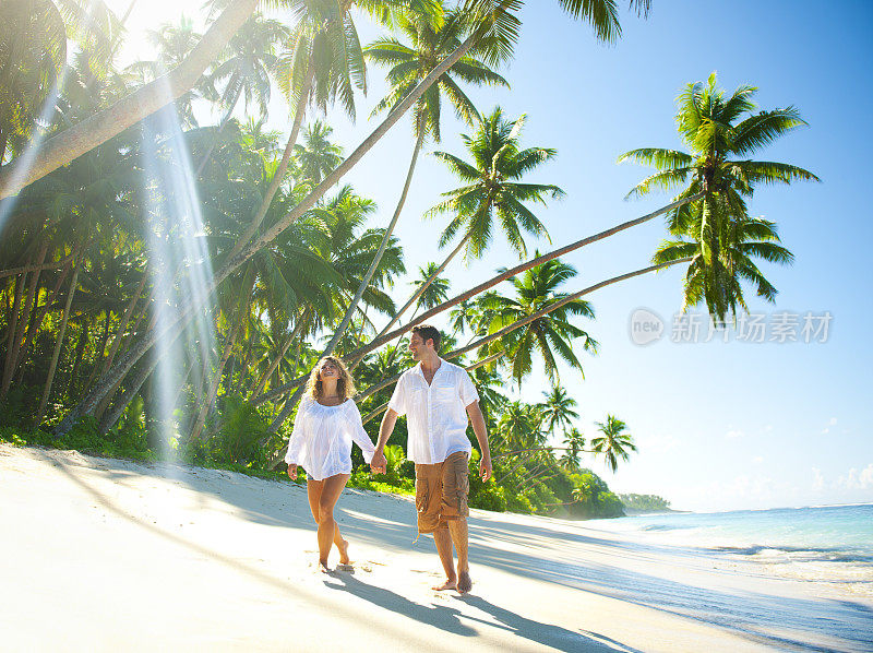 年轻夫妇在一个田园诗般的热带海滩上放松