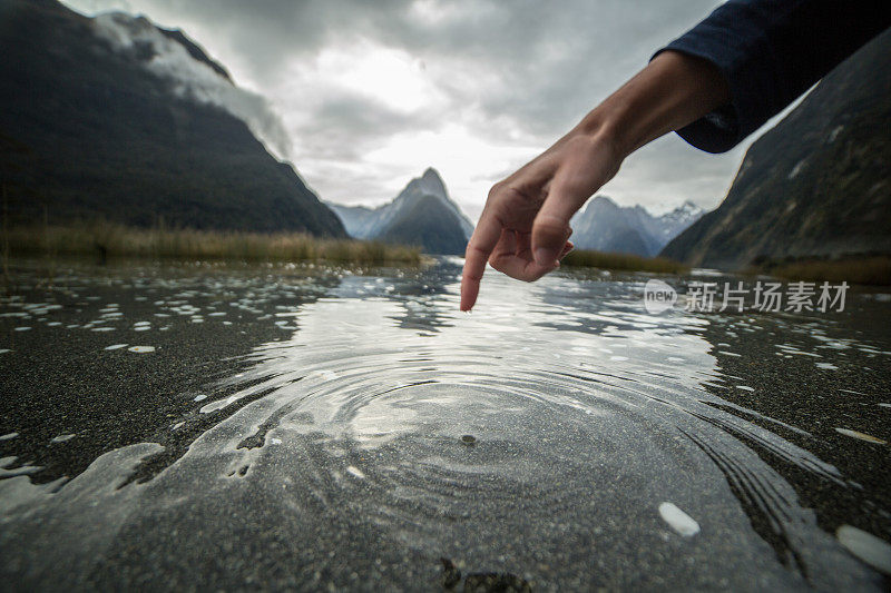 手指触摸新西兰山湖的表面