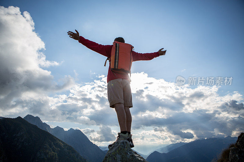 一个登山者张开双臂站在山顶