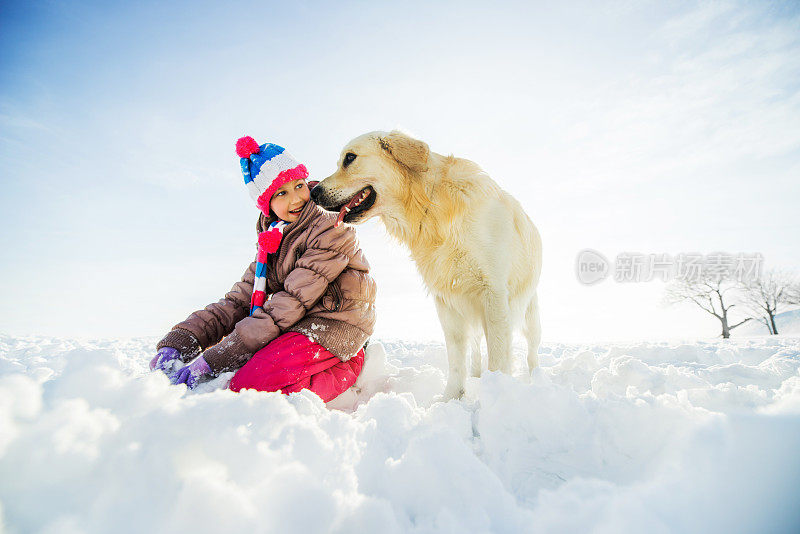 顽皮的女孩和她的狗享受在雪。