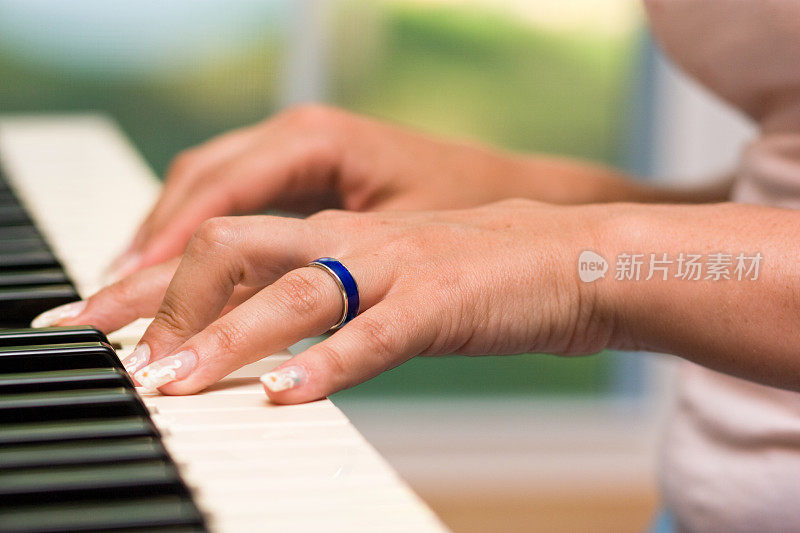 女人的手放在钢琴键盘上