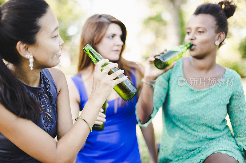 三个年轻女人在公园喝啤酒