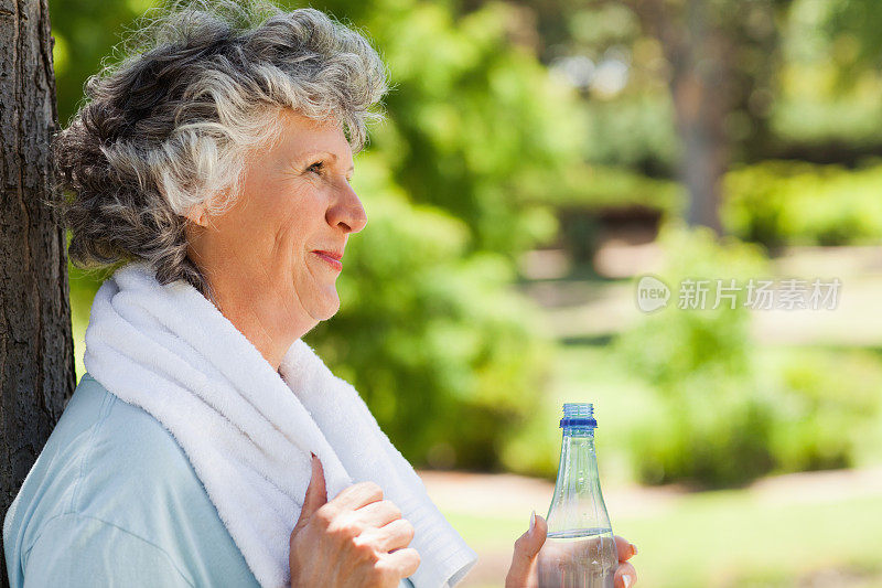 一个靠在一棵老树上的女人的侧视图