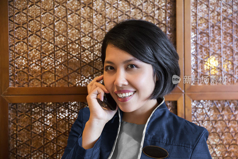 亚洲酒店接待员用智能手机打电话