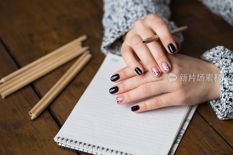 一个修了漂亮指甲的女人在笔记本上画画
