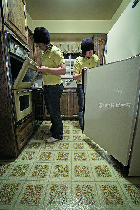 年轻人在厨房看冰箱和炉子