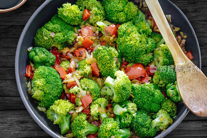 新鲜的夏季沙拉。清炒蔬菜、西兰花、酱油、伊比利亚火腿丁放在质朴的木桌上。健康食品的概念。