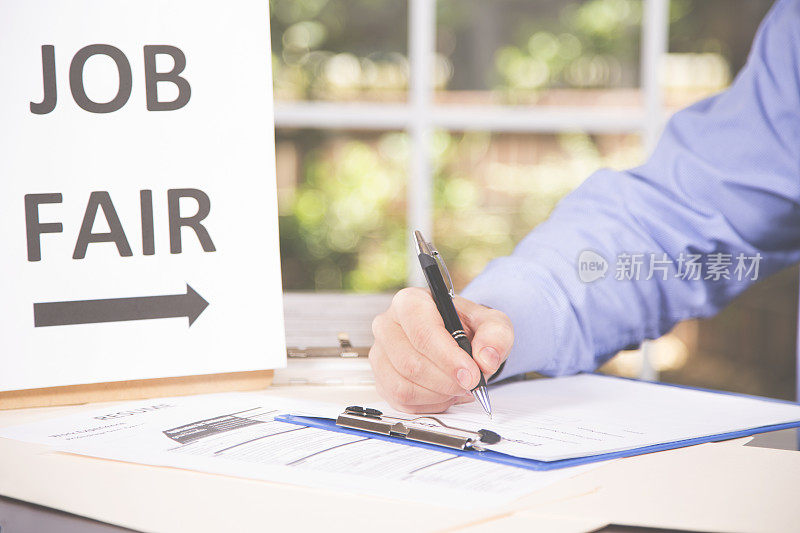 男子在招聘会上登记工作申请和简历。