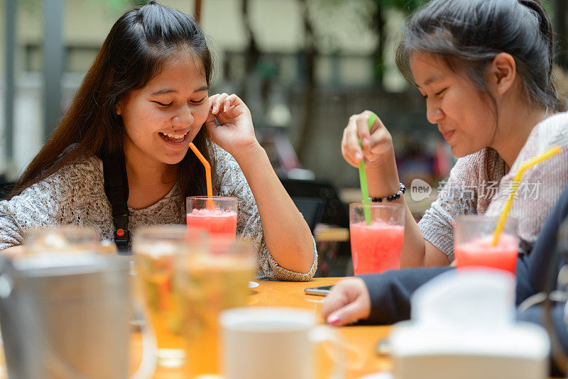 年轻的亚洲女性朋友一起在餐馆里闲逛的照片