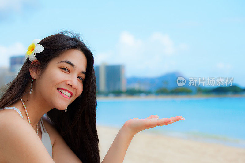 一名少女坐在夏威夷海滩上，背景是钻石头