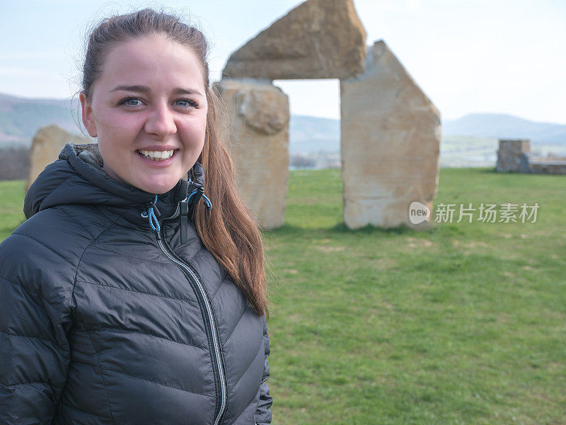 女游客站在巨石阵般的石质建筑纪念碑前