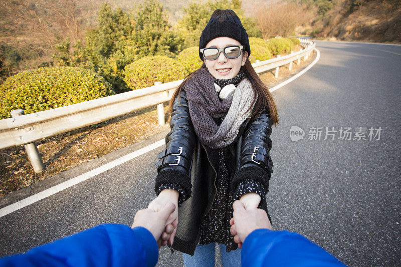 幸福的女朋友牵着男朋友的手在山路上