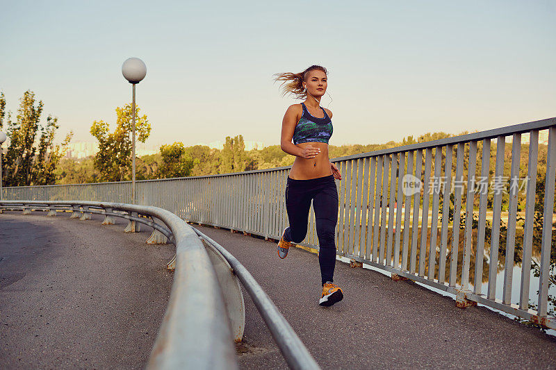一位女性跑步者在城市的一座桥上慢跑
