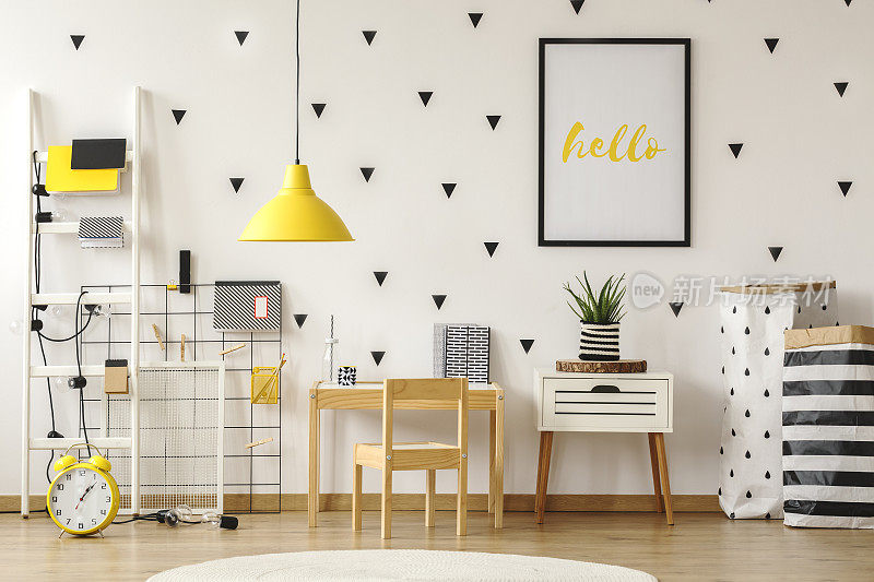 白色墙壁上的黑框海报，斯堪的纳维亚风格的儿童卧室内饰有木制家具和黄色装饰