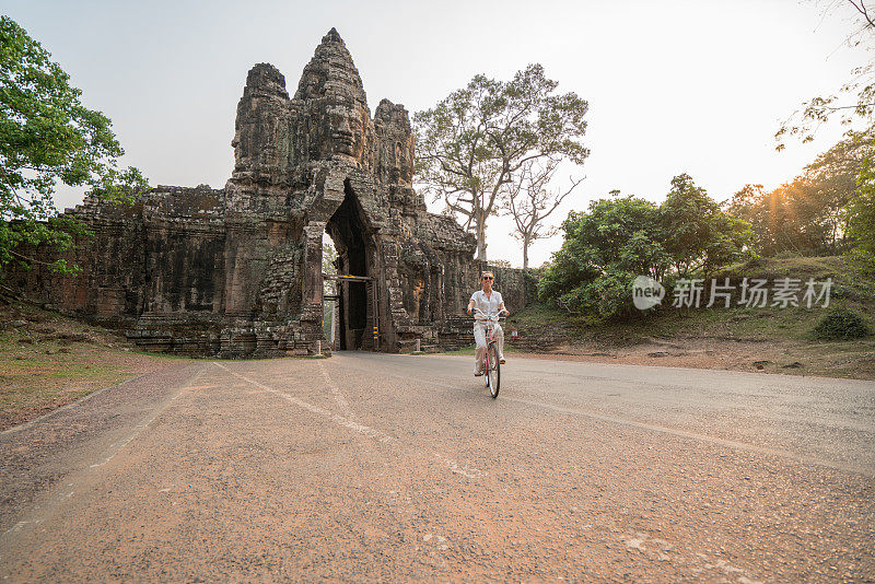 柬埔寨古庙建筑群里骑自行车的年轻女子
