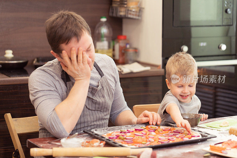爸爸和儿子在厨房里愉快地做披萨