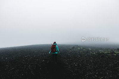 女人背包徒步旅行，虽然火山景观和风在冰岛无处