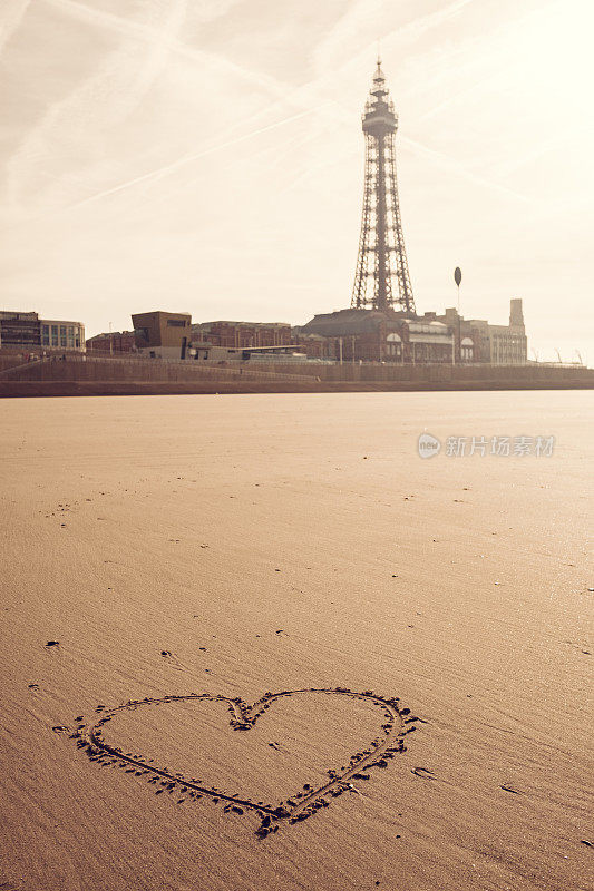 爱的心在沙滩上，黑池塔在远方。