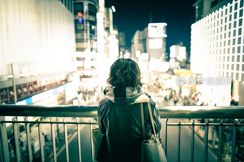 年轻女子在晚上看城市的景色